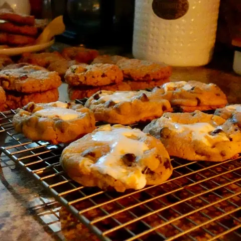 Marshmallow-topped chocolate chip cookies cooling on a wire rack in warm kitchen light